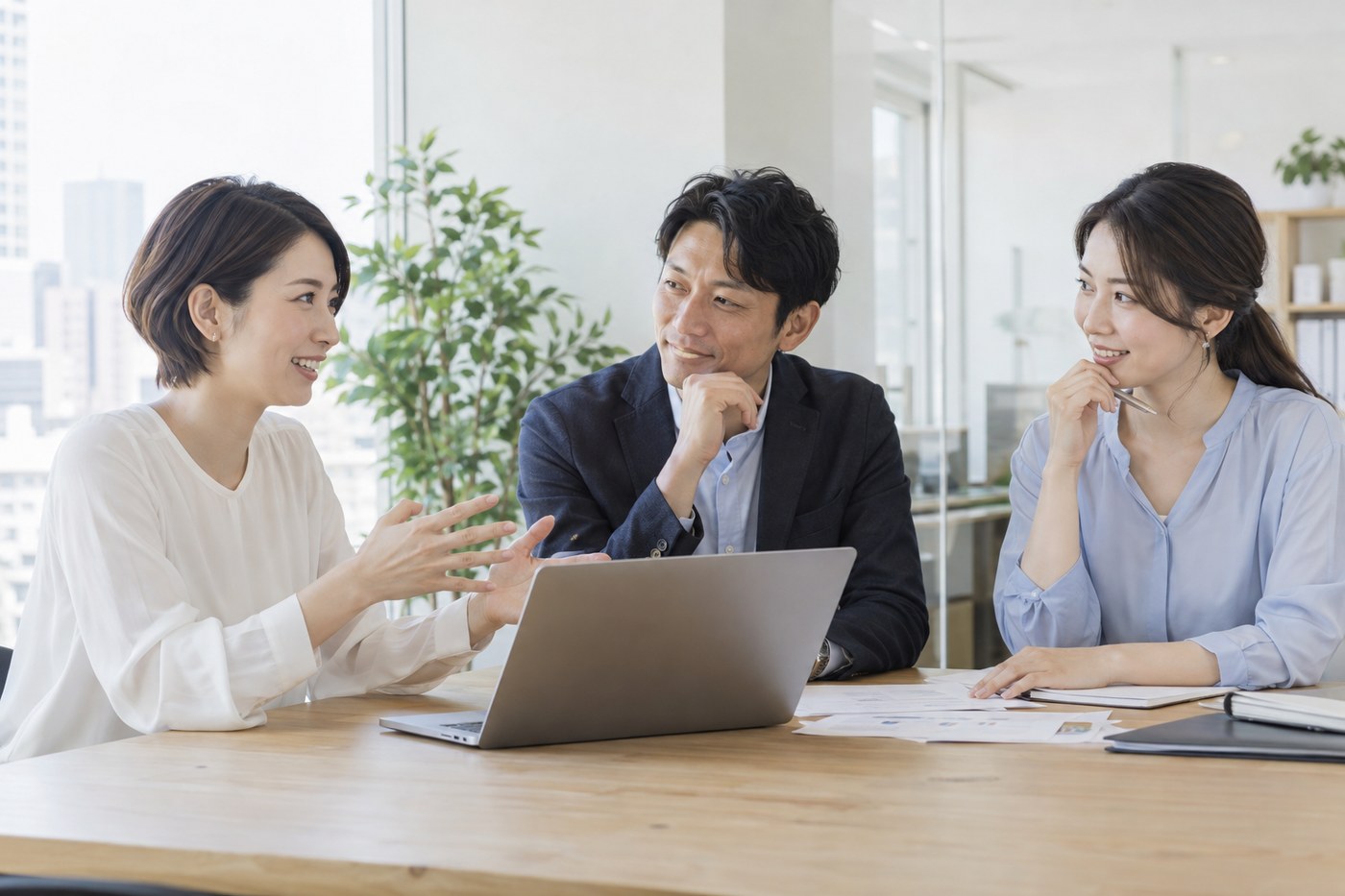 ノートパソコンと資料を囲んで話す架空の日本人3名